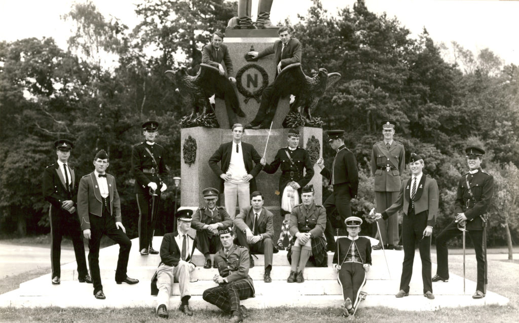 a pohoto of officer cadets wearing random bits of uniform in front of a statue