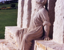 A photograph of the tolpuddle statue showing a seated man dressed in a long basic robe with his head back and eyes closed.