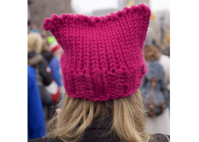 A photograph of a pink knitted hat on a persons head.