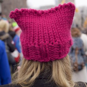 A photograph of a pink knitted hat on a persons head.