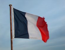 A photograph of the french flag flying in the wind, the far right edge is frayed