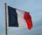 A photograph of the french flag flying in the wind, the far right edge is frayed