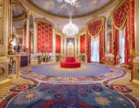 a photo of an opulent room with red and gold decoration and a chandelier