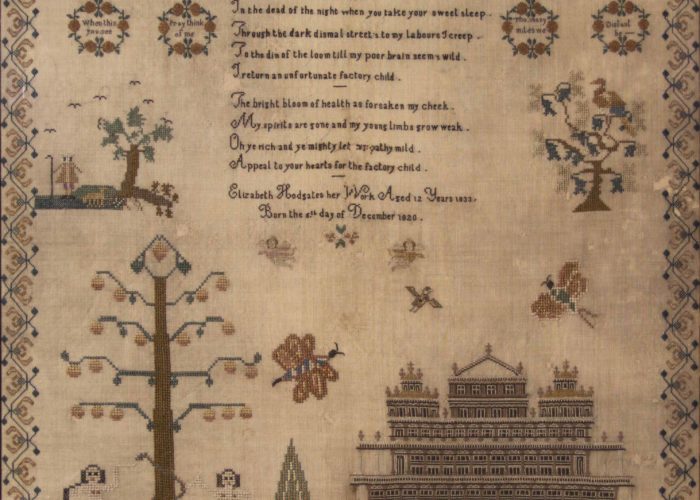 A square piece of fabric which has been embroidered with images of a tree, a building and a poem with a floral border.