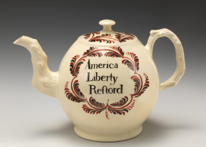 A photo of a white tea pot with red decoration and text that reads 'America Liberty Restord'