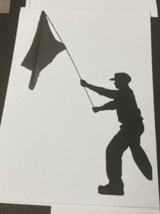 silhouette of figure in hat waving large flag