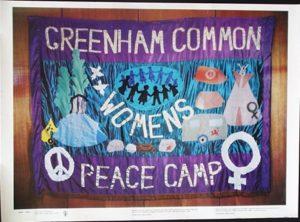 fabric banner in blue and purple reading 'greenham common womens peace camp' 